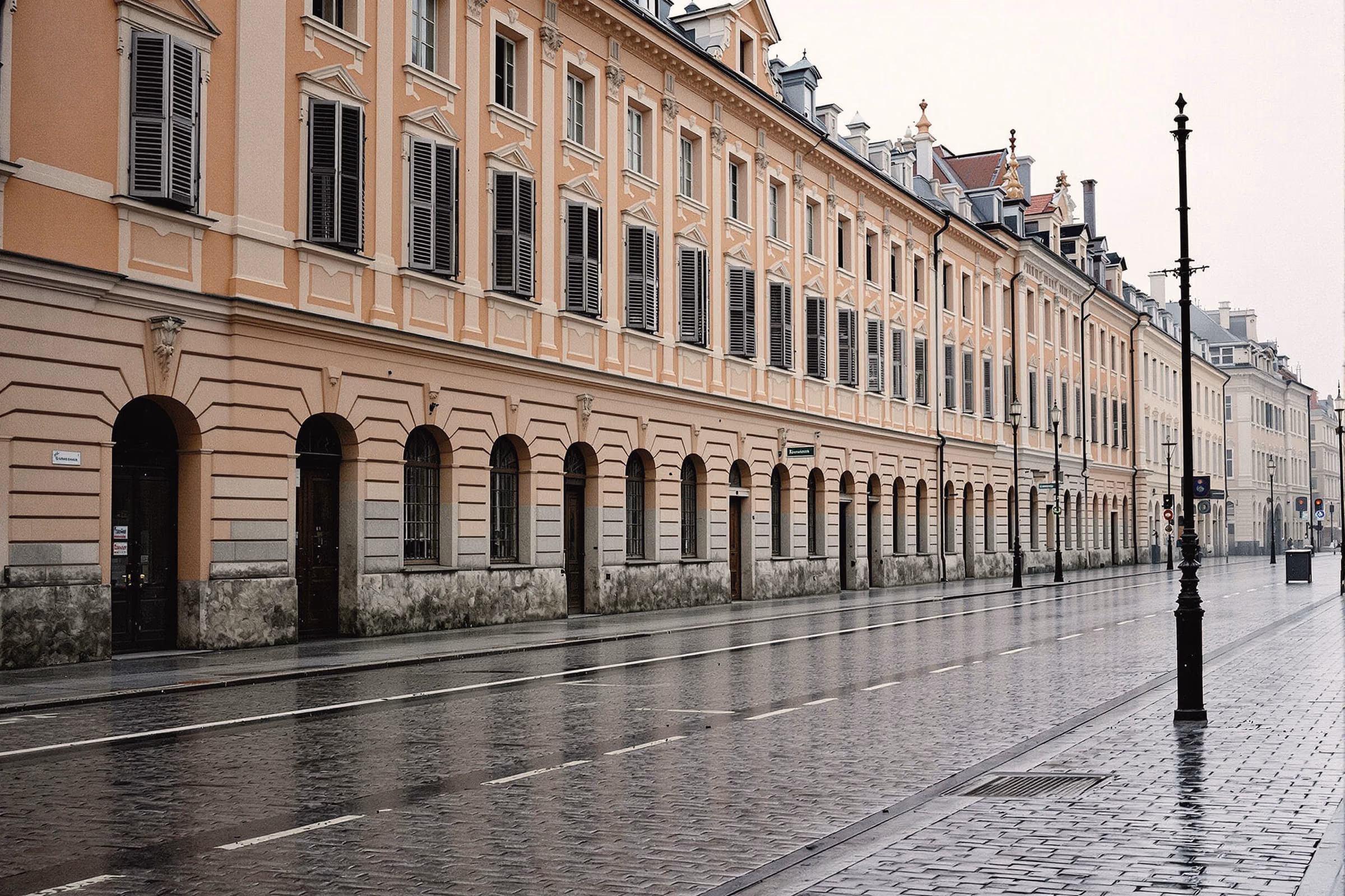 A row of Habsburg-era façades along an empty square after rain